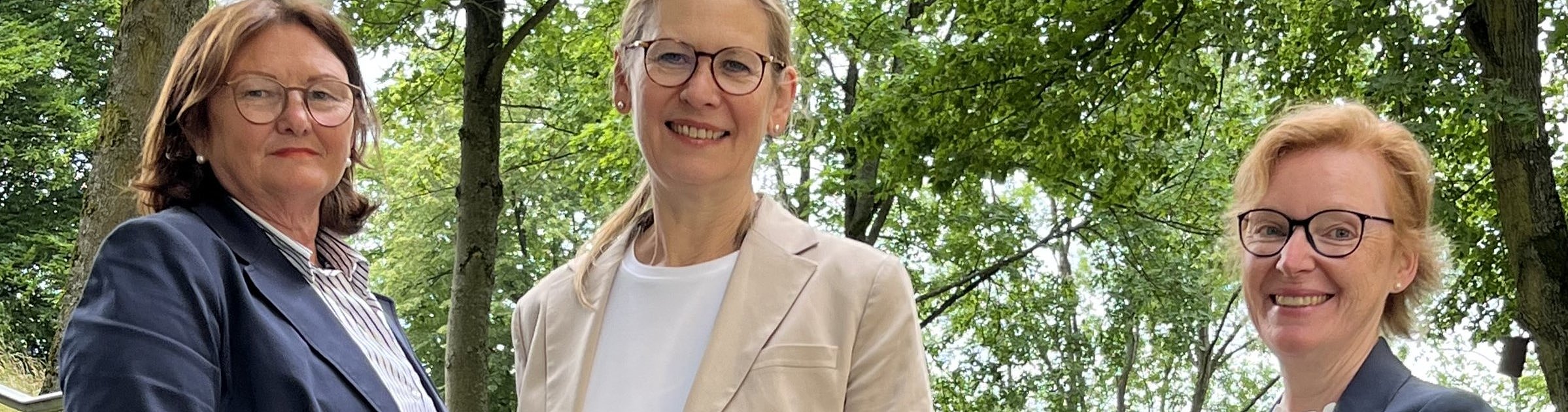 Drei Frauen aus der GeBO-Akademie stehen im Park.