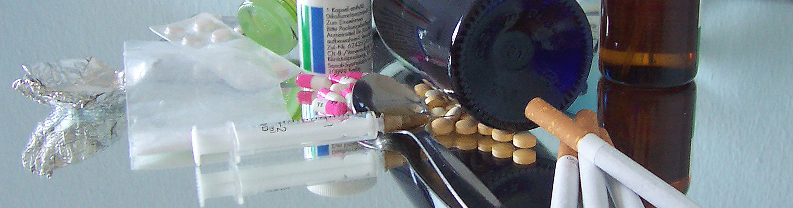 Zigaretten, Alkohol, Spritzen und Medikamente auf einem Tisch