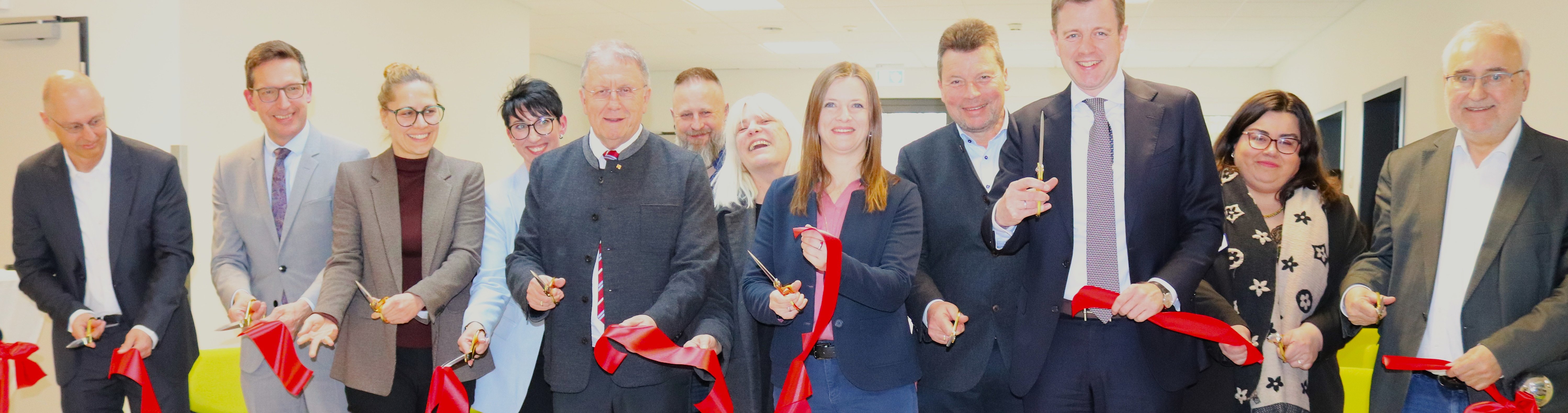Lokale Prominenz aus Politik und von der Klinik durchschneiden ein rotes Band als Zeichen der Eröffnung des Neubaus.